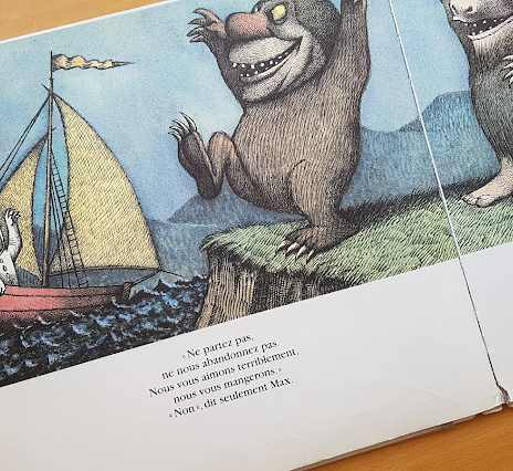 Photo d'une page de l'album "Max et les Maximonstres" : Max part en bateau et les Maximonstres se lamentent depuis la rive. Texte : "Ne partez pas, ne nous abandonnez pas ! Nous vous aimons terriblement, nous vous mangerons ! Non, dit seulement Max.